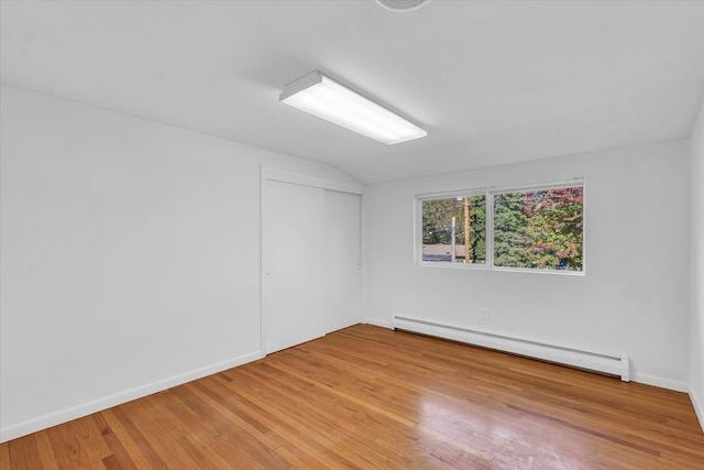 spare room with light wood-type flooring, lofted ceiling, and baseboard heating