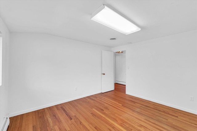 empty room featuring light hardwood / wood-style floors and a baseboard heating unit