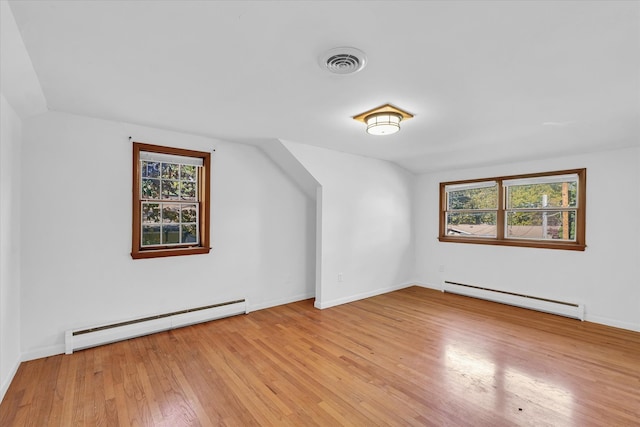 additional living space with baseboard heating, plenty of natural light, and light hardwood / wood-style floors