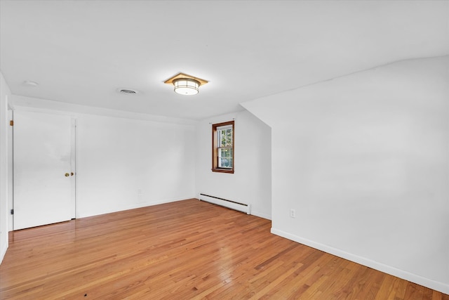 additional living space with a baseboard heating unit and light hardwood / wood-style flooring