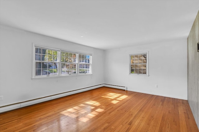 empty room with baseboard heating and light hardwood / wood-style flooring