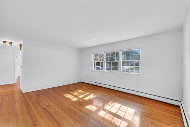 empty room featuring a baseboard heating unit and light hardwood / wood-style floors