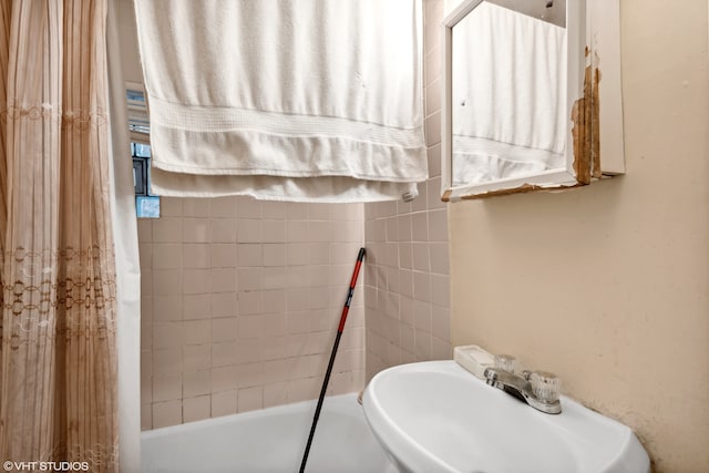 bathroom with shower / bathtub combination with curtain and sink