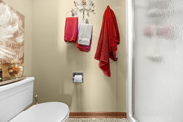 bathroom with a shower with door, tile patterned flooring, and toilet