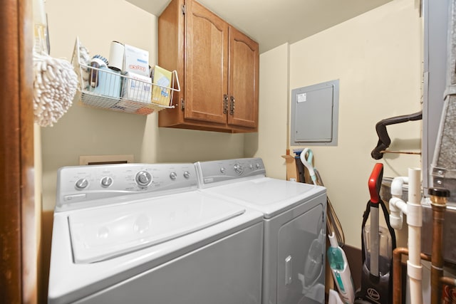 laundry room with electric panel, cabinets, and washing machine and clothes dryer