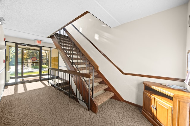 staircase featuring carpet flooring and a textured ceiling