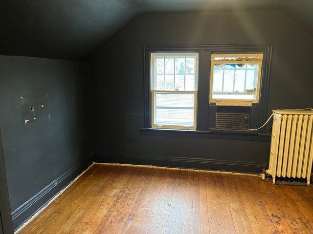 bonus room with hardwood / wood-style floors, radiator, cooling unit, and lofted ceiling