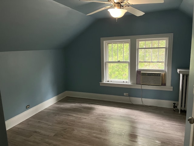 additional living space featuring cooling unit, wood-type flooring, lofted ceiling, radiator, and ceiling fan