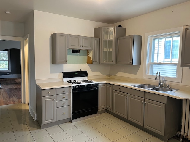 kitchen with gas range oven, light wood-type flooring, gray cabinets, sink, and baseboard heating