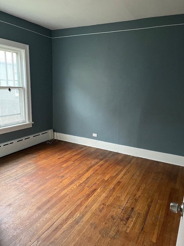 spare room with wood-type flooring and a baseboard heating unit