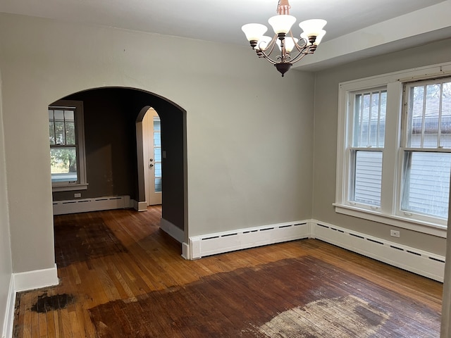 empty room featuring a baseboard radiator, dark hardwood / wood-style flooring, a healthy amount of sunlight, and a chandelier