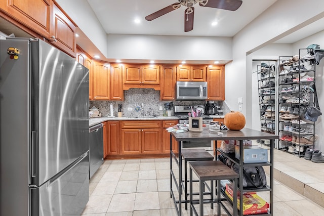 kitchen featuring stainless steel appliances, light tile patterned flooring, sink, a breakfast bar area, and decorative backsplash