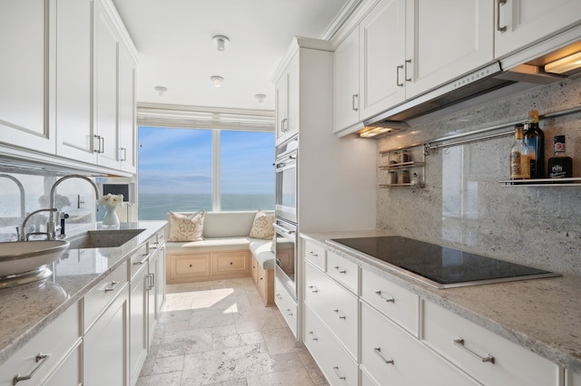 kitchen featuring white cabinets, backsplash, black electric cooktop, and a water view