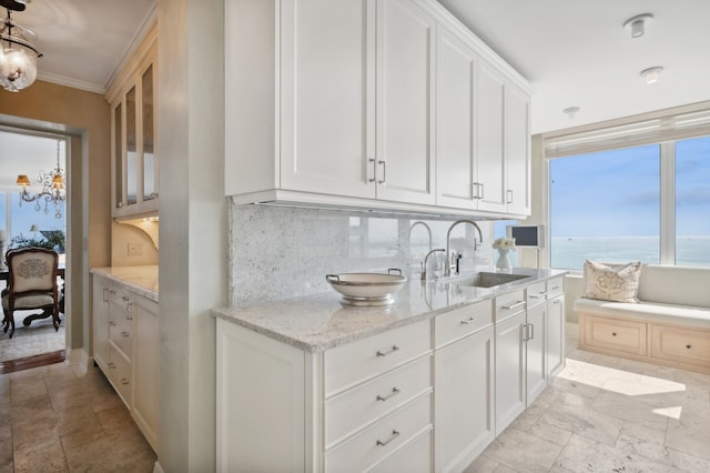 kitchen with white cabinets, a water view, sink, decorative backsplash, and a chandelier