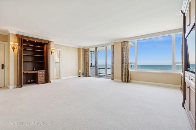 unfurnished living room featuring light carpet, a water view, and ornamental molding