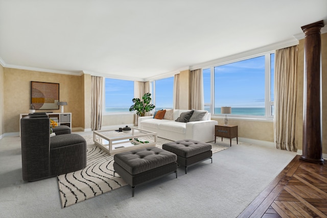 living room with decorative columns, plenty of natural light, a water view, and ornamental molding