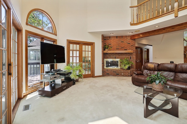 carpeted living room with a brick fireplace, a towering ceiling, and french doors