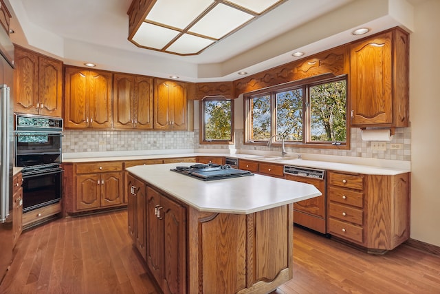 kitchen featuring black double oven, paneled dishwasher, sink, and light wood-type flooring