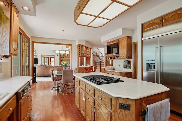 kitchen featuring stainless steel appliances, decorative light fixtures, a chandelier, a center island, and light wood-type flooring