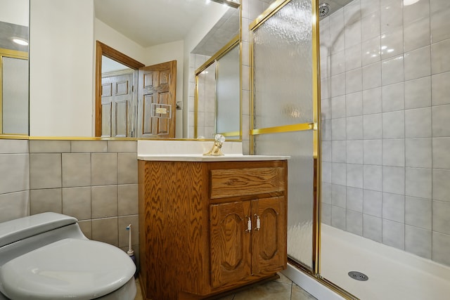 bathroom with vanity, an enclosed shower, tile patterned floors, toilet, and tile walls