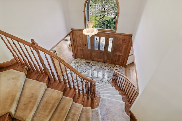 foyer entrance with light hardwood / wood-style floors, a high ceiling, and an inviting chandelier