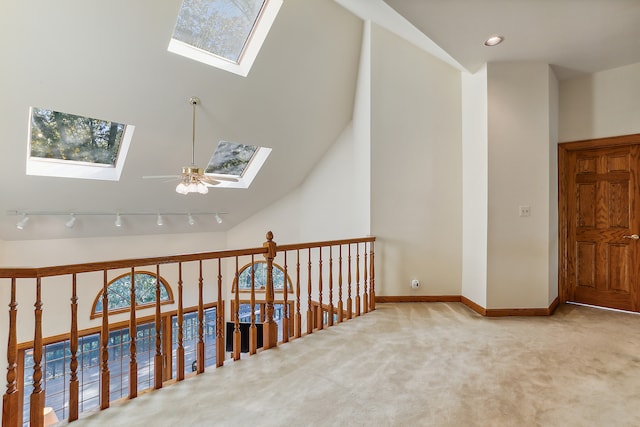 hall with a healthy amount of sunlight, light carpet, and lofted ceiling with skylight