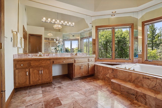 bathroom featuring vanity, tiled tub, and an inviting chandelier