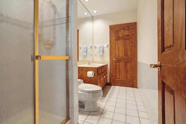 bathroom with toilet, tile patterned floors, tile walls, vanity, and walk in shower