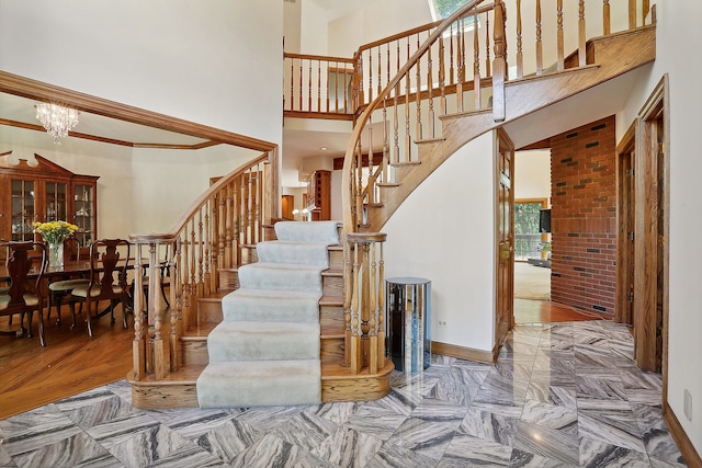 stairway with ornamental molding, a high ceiling, a healthy amount of sunlight, and hardwood / wood-style flooring