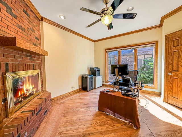 office space featuring a brick fireplace, light hardwood / wood-style flooring, ceiling fan, and crown molding