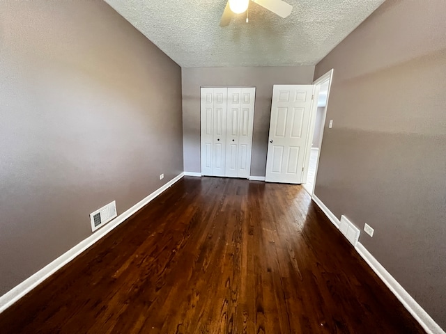 unfurnished bedroom with a textured ceiling, dark hardwood / wood-style flooring, ceiling fan, and a closet