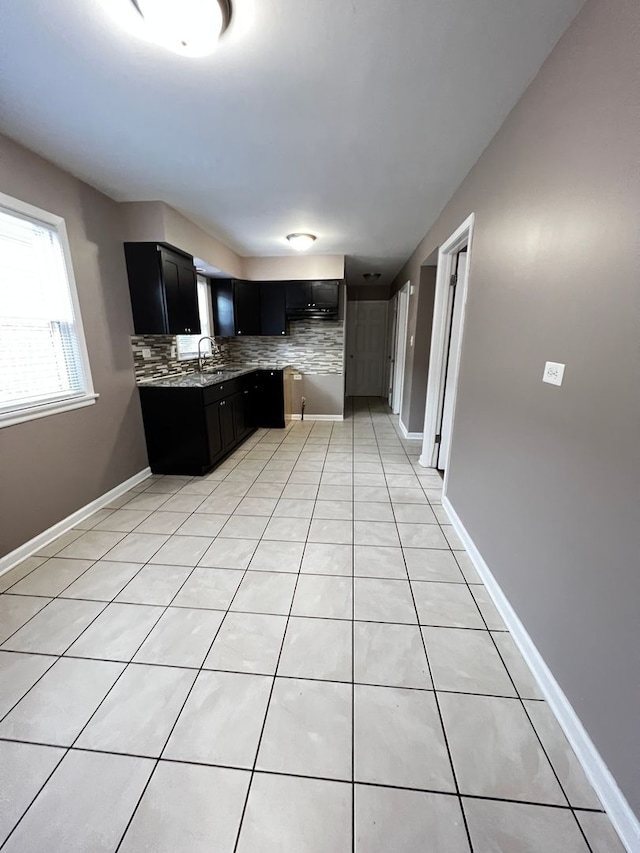 kitchen featuring light tile patterned floors, light stone countertops, sink, and decorative backsplash