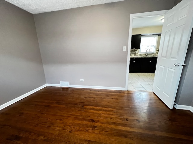 empty room with sink, a textured ceiling, and light hardwood / wood-style flooring