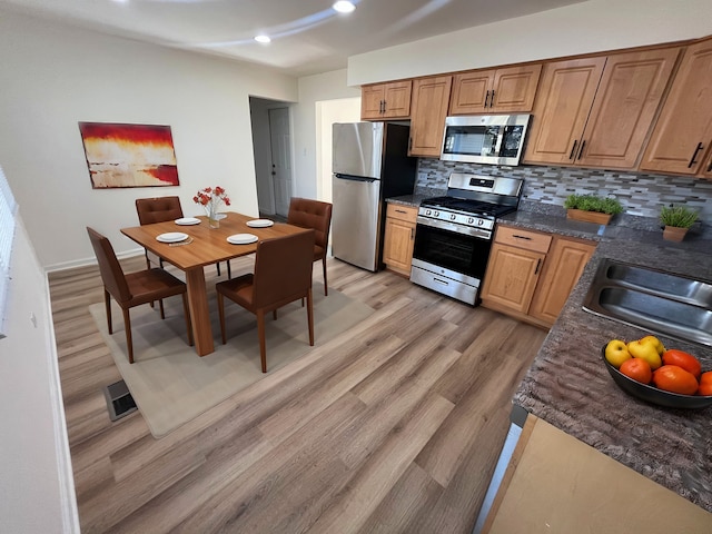 kitchen featuring sink, light hardwood / wood-style flooring, appliances with stainless steel finishes, and tasteful backsplash