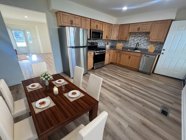 kitchen with stainless steel appliances, tasteful backsplash, light hardwood / wood-style floors, and sink