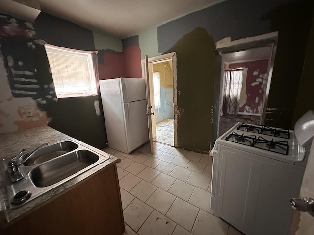 kitchen featuring light tile patterned flooring, white appliances, and sink