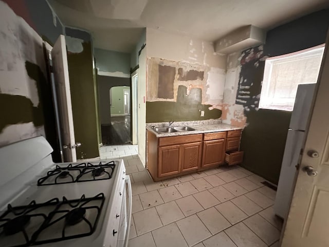 kitchen with white gas range, sink, and light tile patterned floors