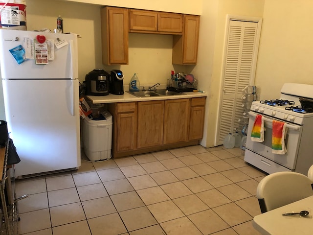 kitchen with light tile patterned floors, white appliances, and sink