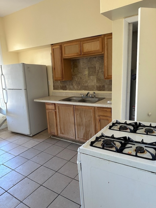 kitchen featuring light tile patterned floors, white appliances, backsplash, and sink