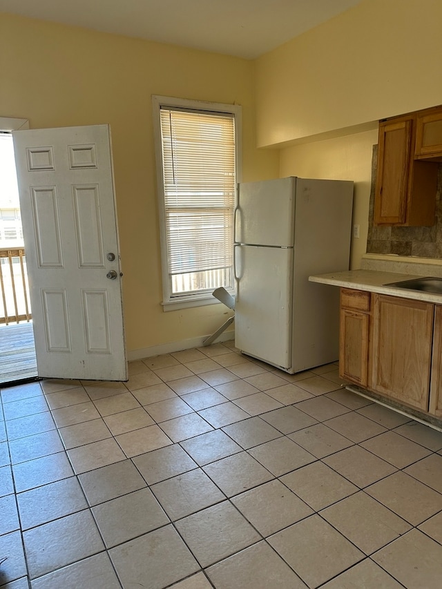 kitchen featuring light tile patterned floors, sink, white refrigerator, and decorative backsplash