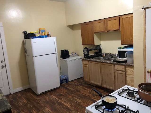 kitchen with white appliances, washer / dryer, sink, and dark hardwood / wood-style flooring