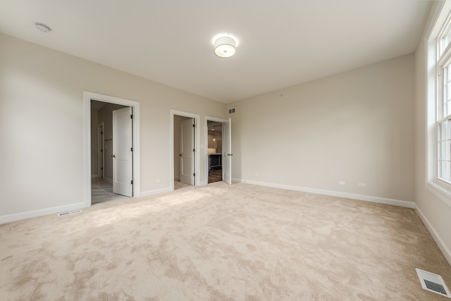 unfurnished bedroom featuring ensuite bath and light carpet