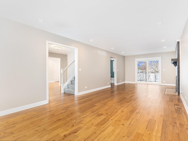 unfurnished living room with light wood-type flooring and a brick fireplace