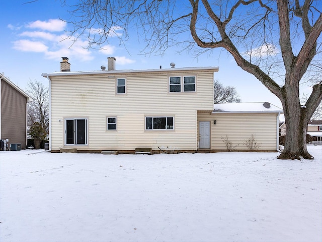 snow covered rear of property with central AC unit