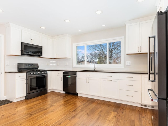 kitchen with sink, white cabinets, light hardwood / wood-style flooring, and stainless steel appliances