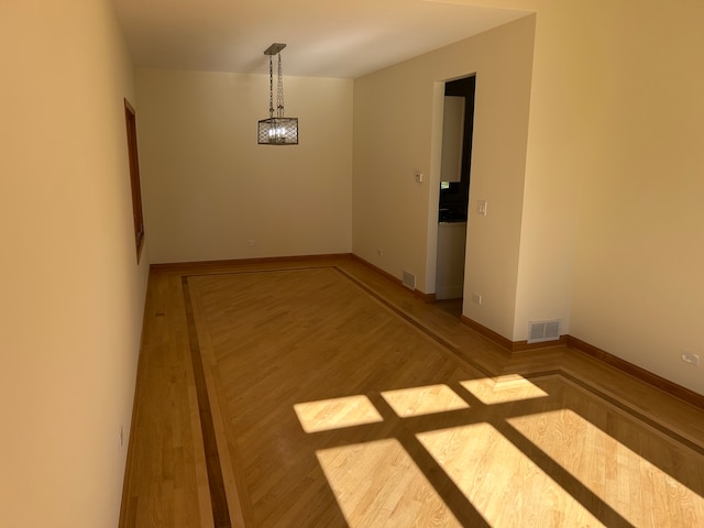 unfurnished room with wood-type flooring and a notable chandelier