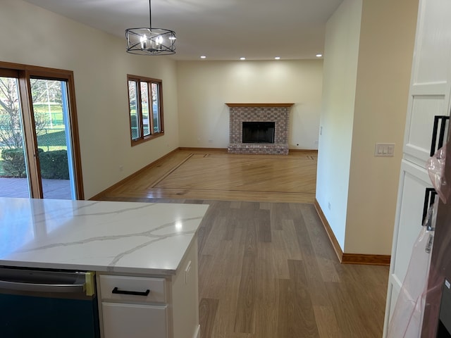 kitchen with white cabinets, light wood-type flooring, decorative light fixtures, and light stone countertops