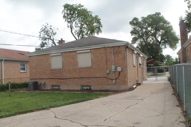 view of side of property featuring central air condition unit and a yard