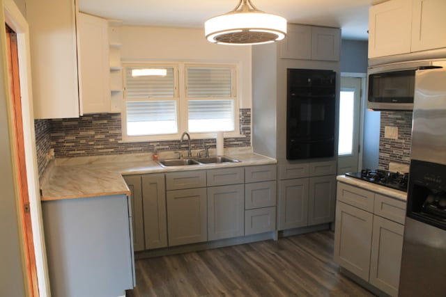 kitchen featuring black appliances, sink, backsplash, and decorative light fixtures