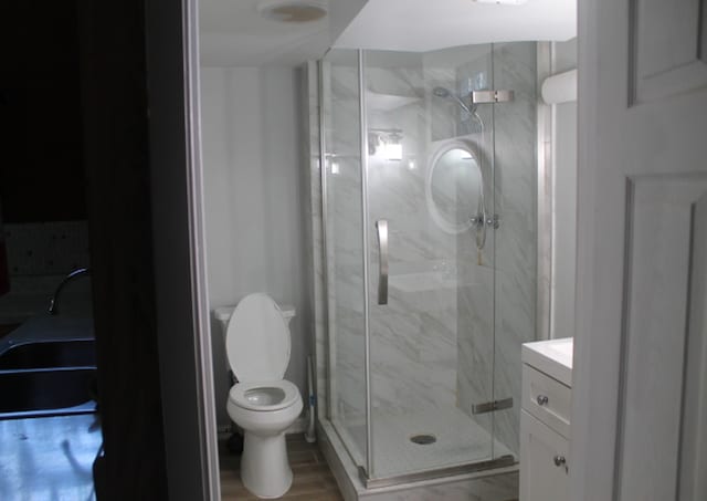 bathroom with hardwood / wood-style floors, walk in shower, vanity, and toilet